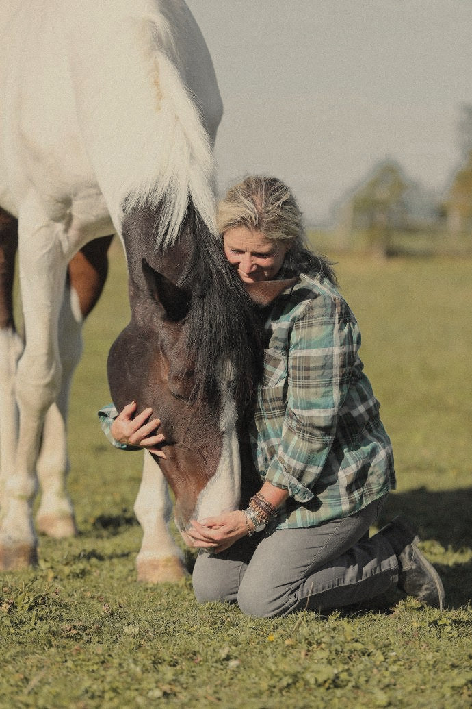 Karin Kalberer kniet auf der Weide und hält den Kopf ihres Schecken im Arm